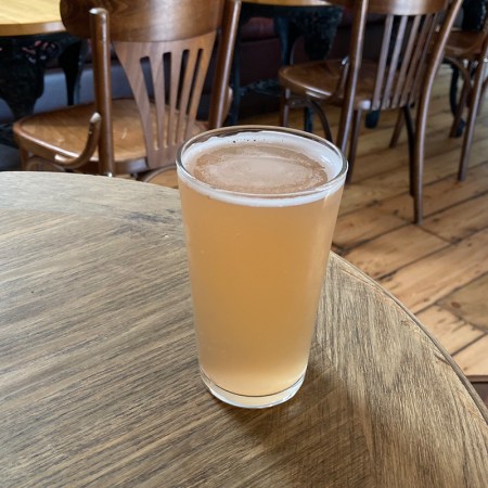 A pint of rhubarb cider standing on a table.